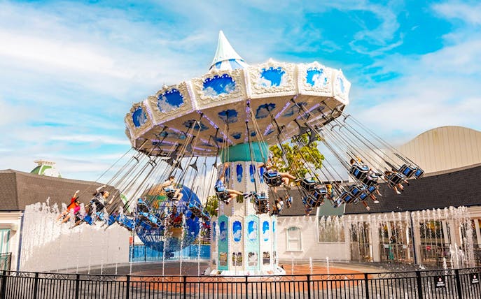 People enjoying a carousel ride at Dreamworld with fountains in the foreground.