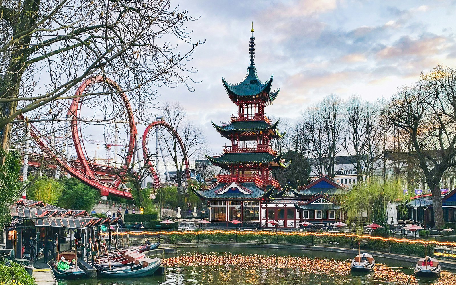 Tivoli Gardens illuminated pagoda and roller coaster at dusk.