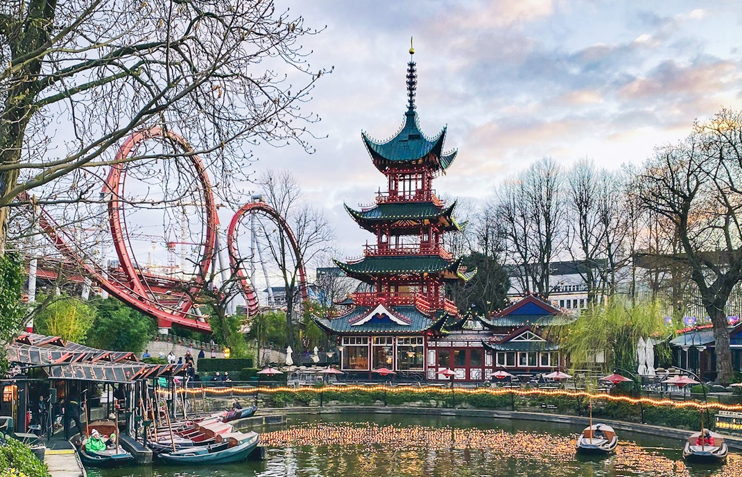 Pagoda and roller coaster at Tivoli Gardens, Copenhagen, with boats on the lake.