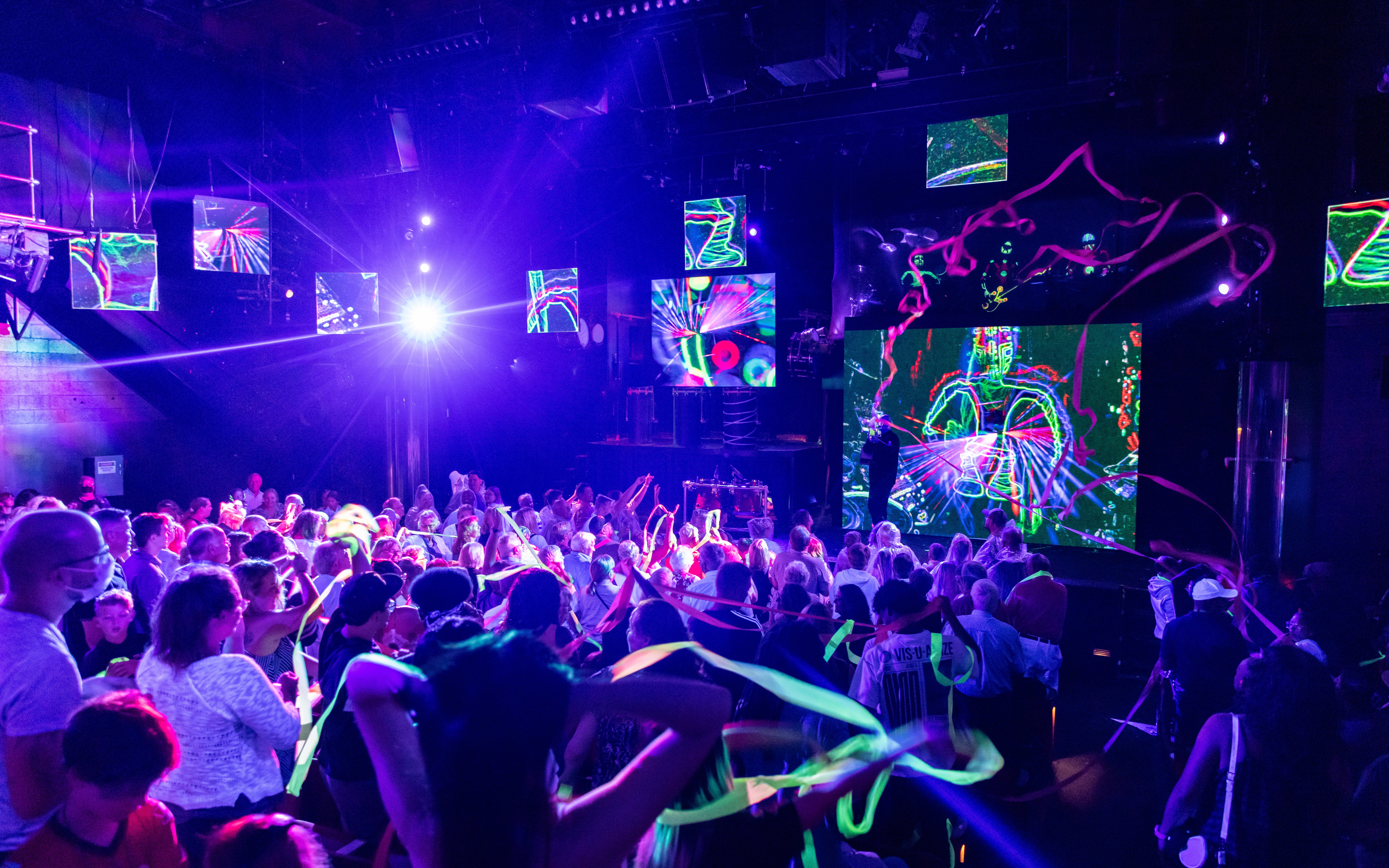 Blue Man Group performing on stage with vibrant lights and audience in Orlando.