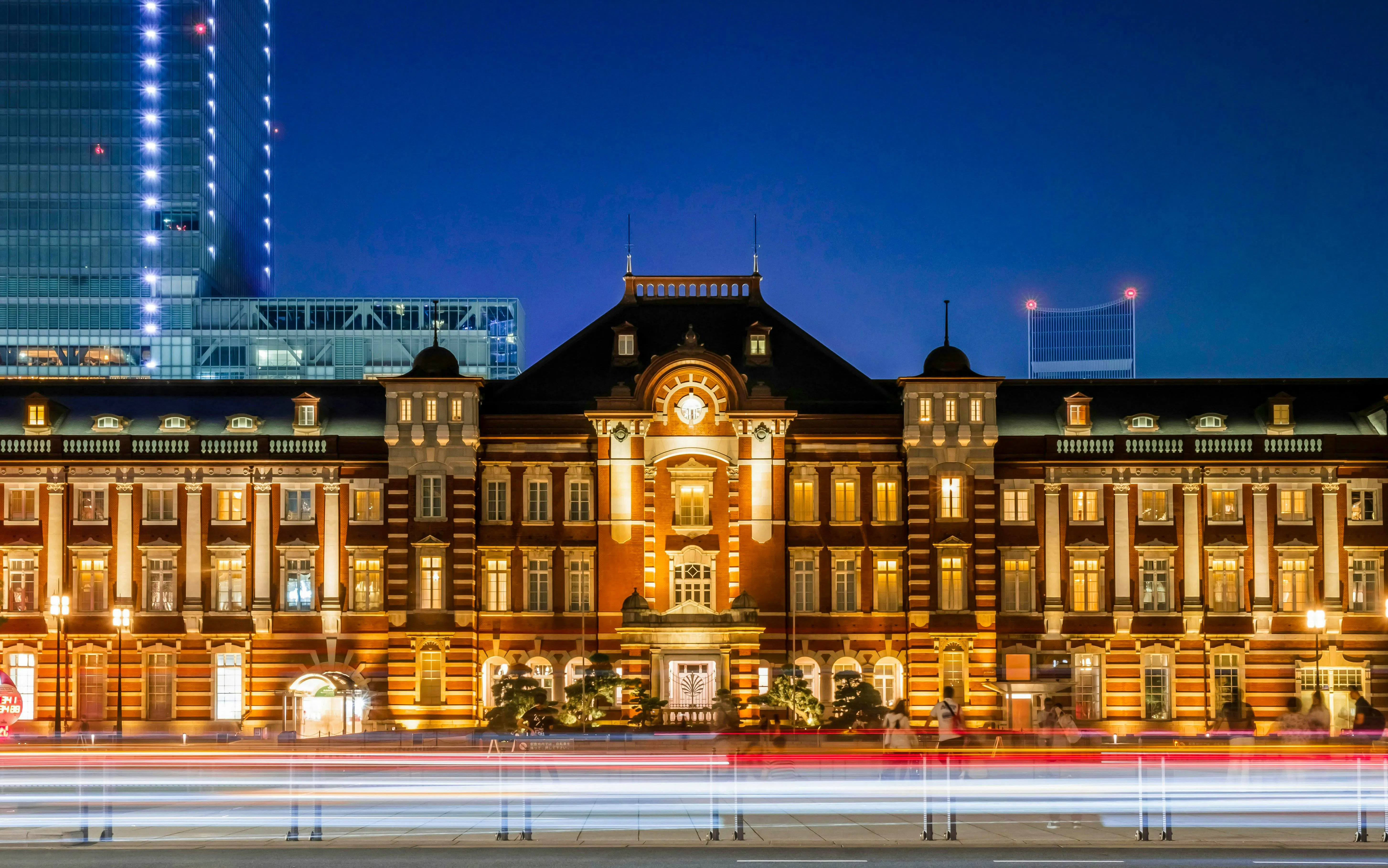 Tokyo Station illuminated at night with light trails in the foreground.