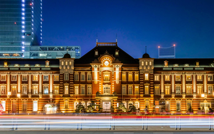 Tokyo Station illuminated at night with light trails in the foreground.