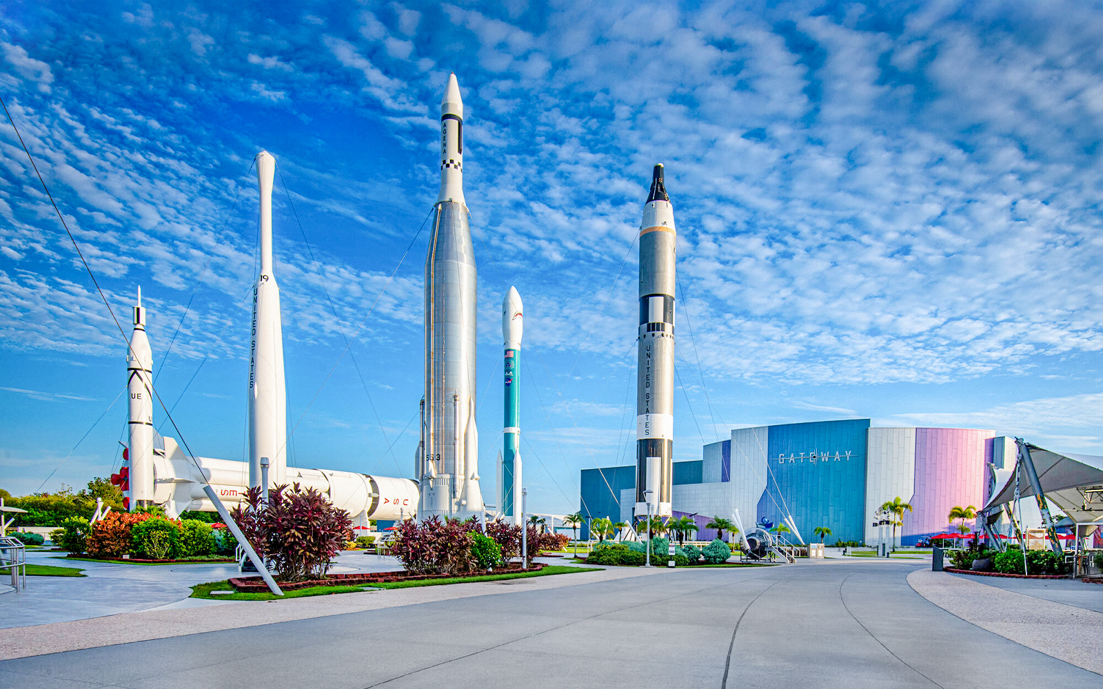 Kennedy Space Center facade with rockets on display under a blue sky.