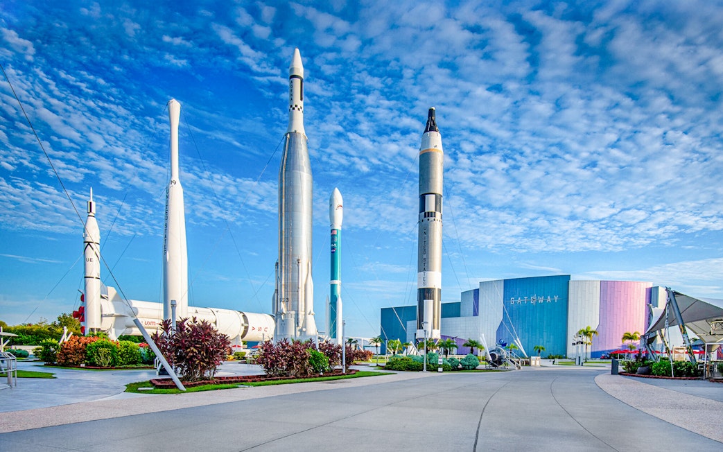 Kennedy Space Center facade with rockets on display under a blue sky.