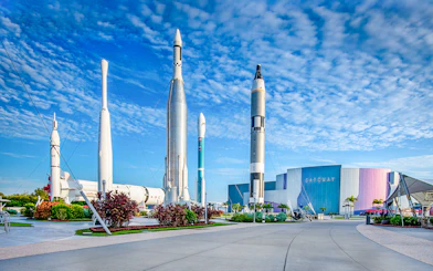 Kennedy Space Center facade with rockets on display under a blue sky.