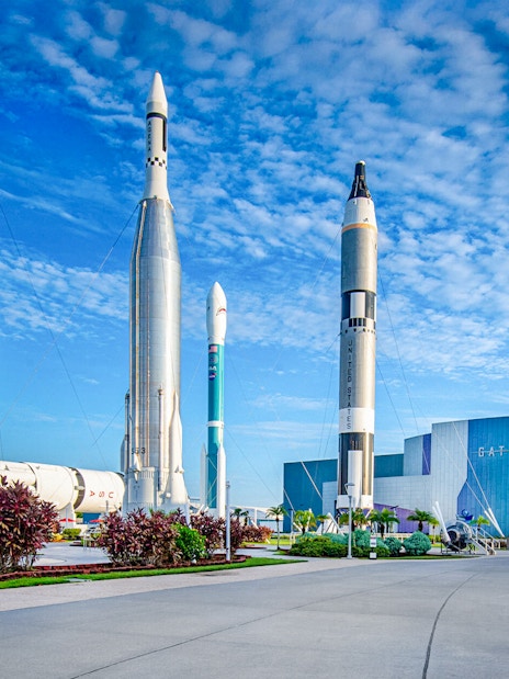Kennedy Space Center facade with rockets on display under a blue sky.