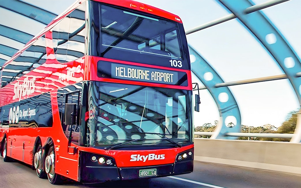 Skybus double-decker heading to Melbourne Airport on a highway bridge.