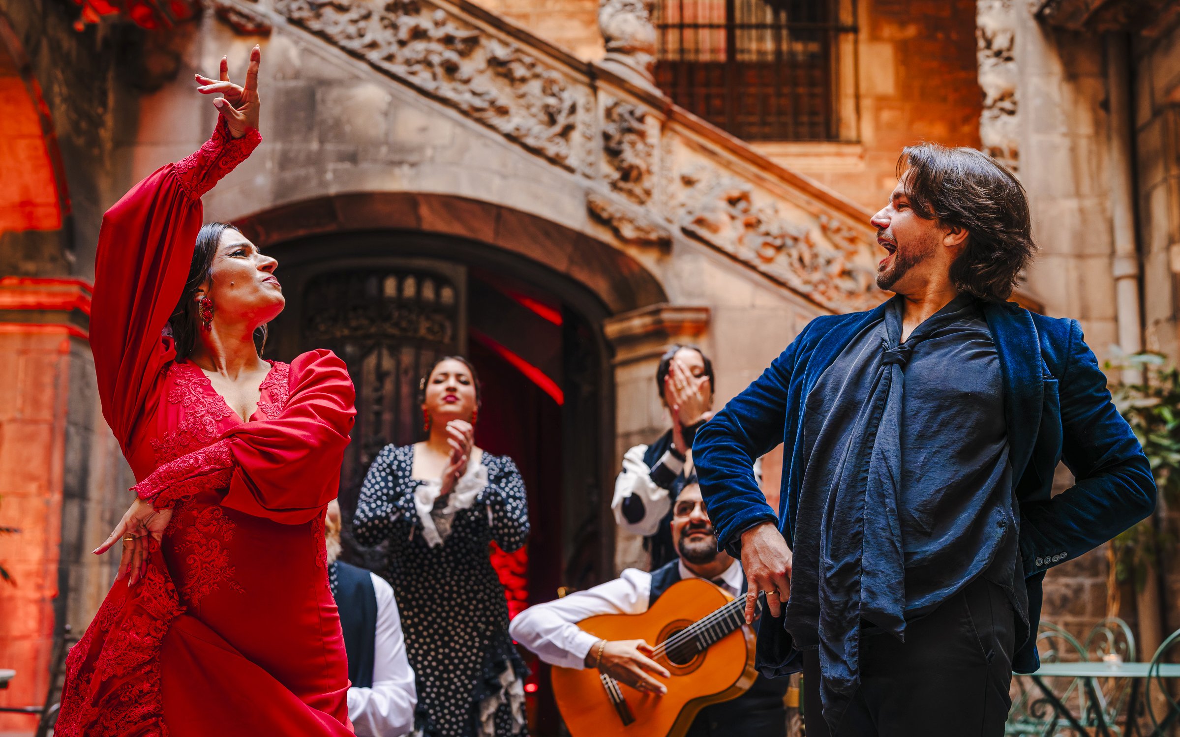 Flamenco dancers performing at Palau Dalmases with guitarist in background.
