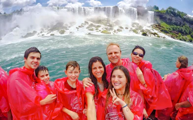 Tourists in red ponchos on a Niagara Falls cruise with the waterfall in the background.