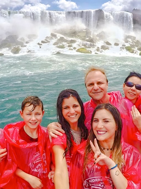 Tourists in red ponchos on a Niagara Falls cruise with the waterfall in the background.
