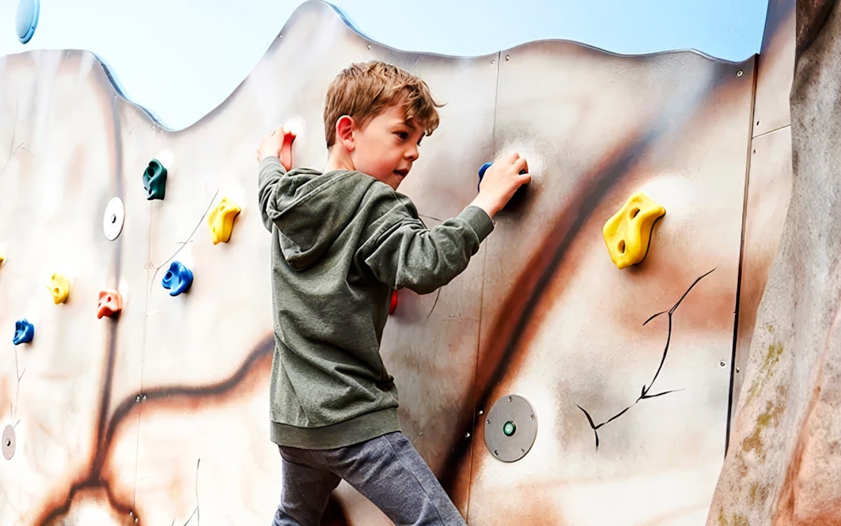 Child climbing a colorful rock wall at LEGOLAND Billund.