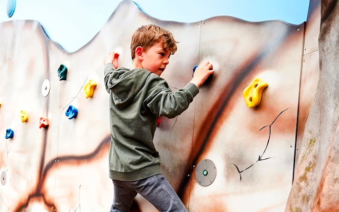 Child climbing a colorful rock wall at LEGOLAND Billund.