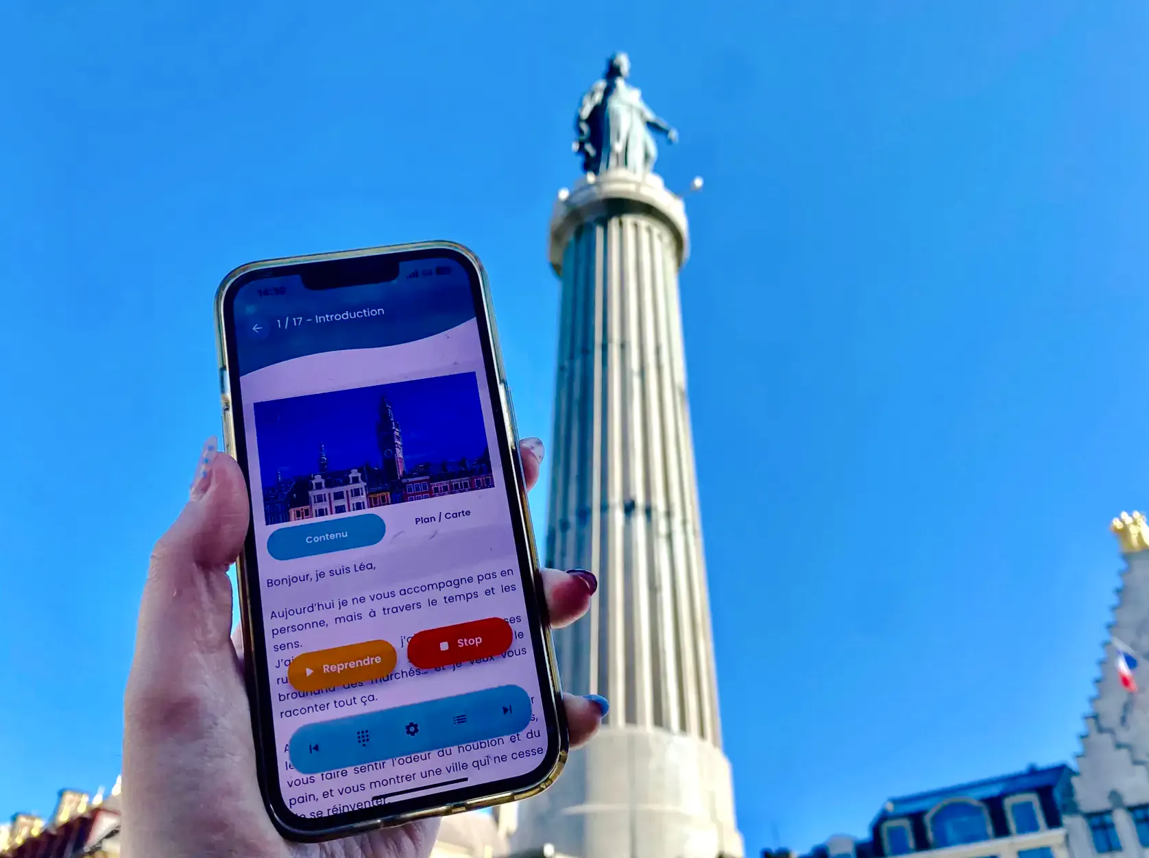 Smartphone displaying audio guide app in front of Lille column during brewery tour.