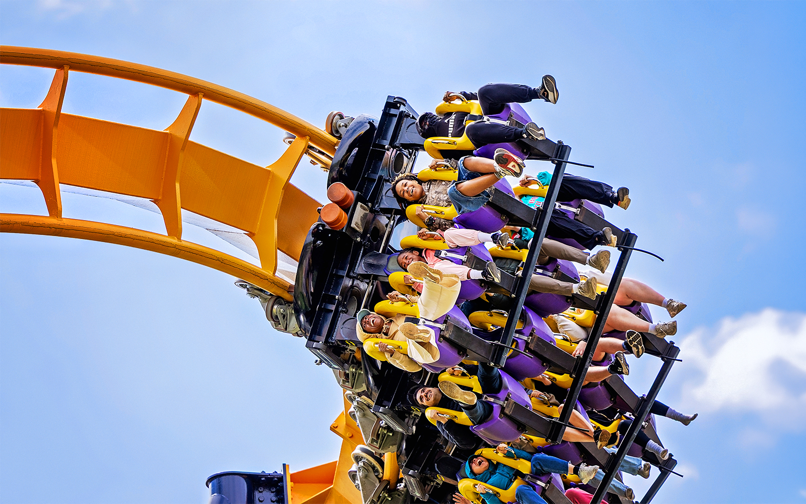 Riders on BATMAN™ The Ride roller coaster at Six Flags Great America, upside down on a loop.