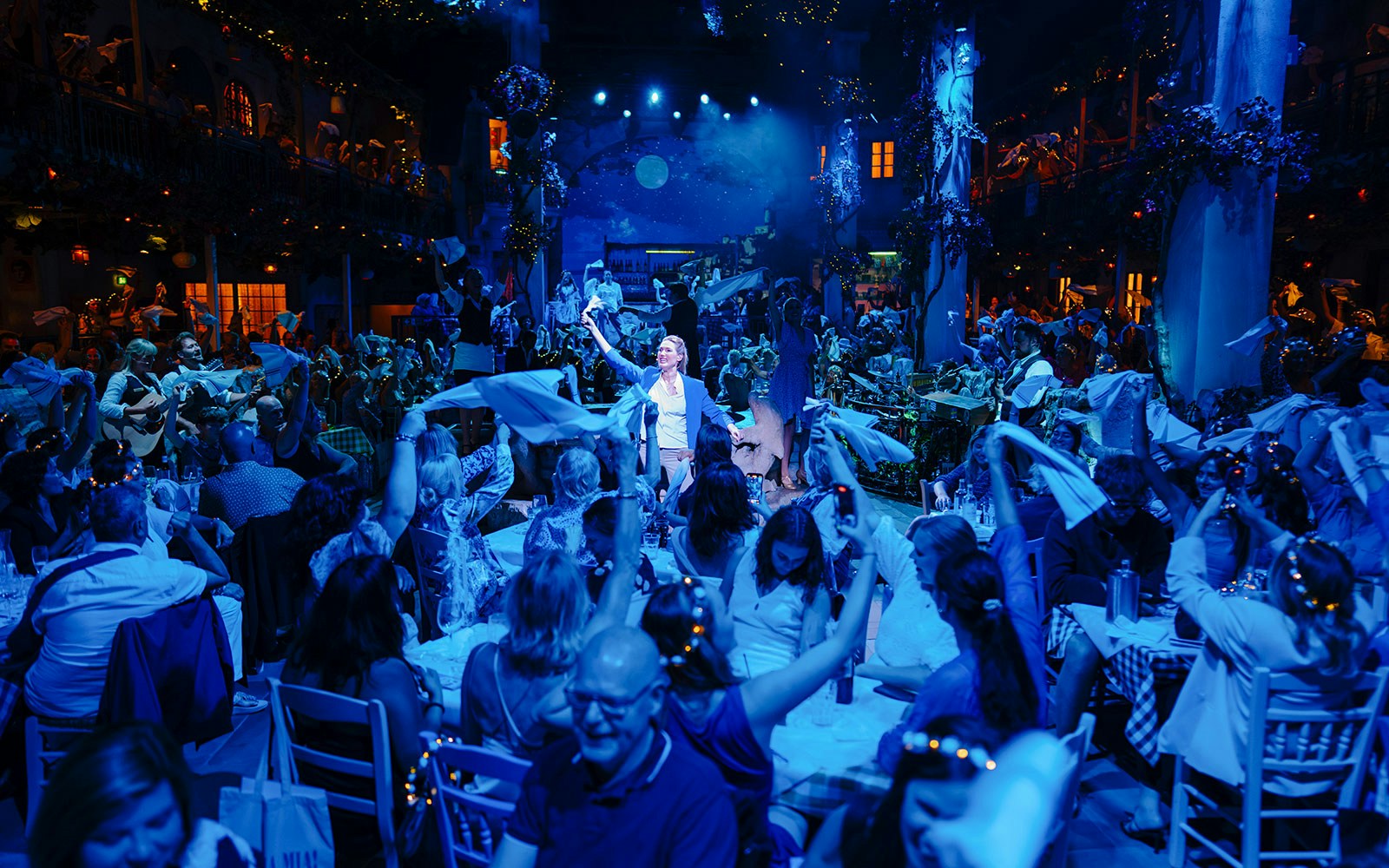Crowd enjoying Mamma Mia! The Party with performers and lively atmosphere.