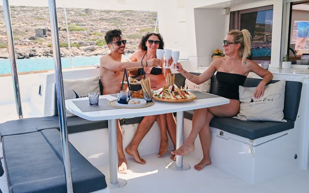 Guests enjoying drinks on a luxury catamaran cruise near Dia Island, Crete.