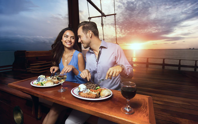 Couple dining on a sunset cruise in Cancun with ocean view.