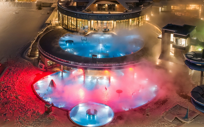 Tourists enjoying Chochołow Thermal Baths with colorful lights, Zakopane transfer included.
