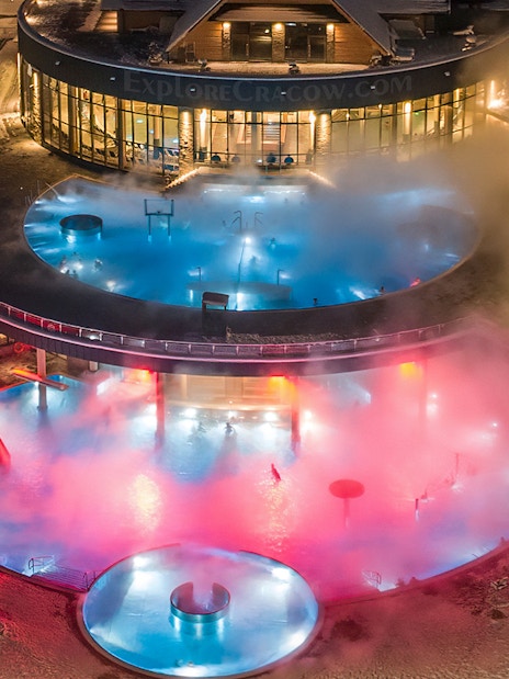 Tourists enjoying Chochołow Thermal Baths with colorful lights, Zakopane transfer included.