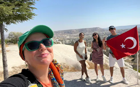 Tourists enjoying a Private Mix Tour in Cappadocia with Turkish flag and scenic landscape.