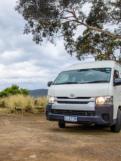 Tour van parked near a globe sculpture on Bruny Island, Tasmania.