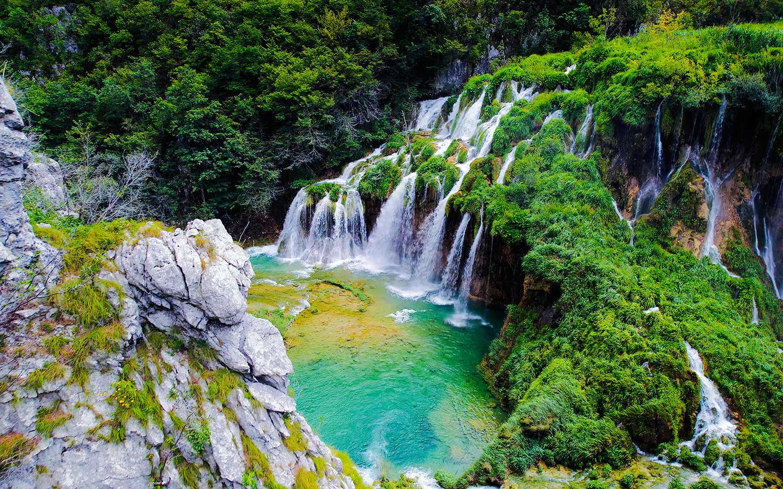 Waterfall cascading over lush greenery in Plitvice Lakes National Park, Croatia.