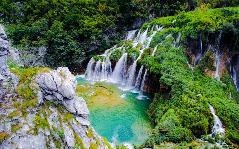 Waterfall cascading over lush greenery in Plitvice Lakes National Park, Croatia.