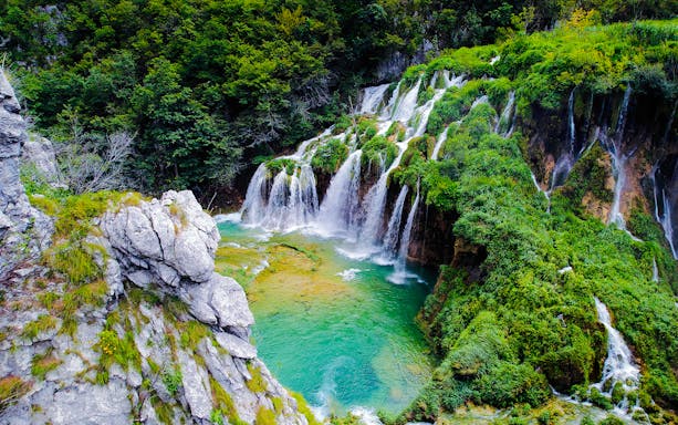 Waterfall cascading over lush greenery in Plitvice Lakes National Park, Croatia.