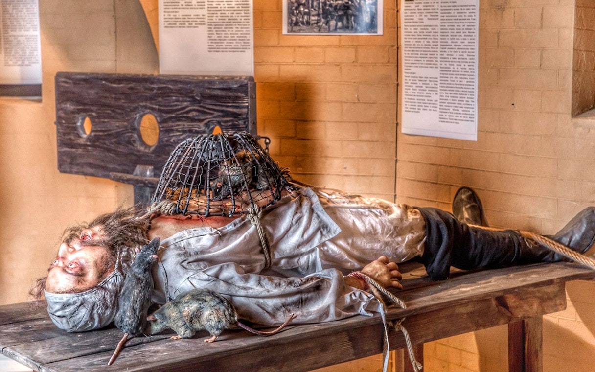 Medieval Torture Museum exhibit with a figure on a table, rats, and a cage.