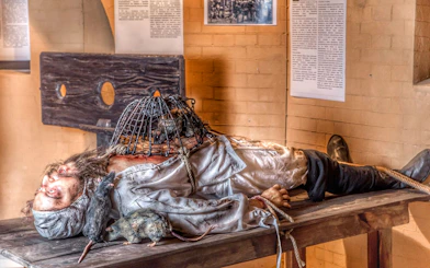 Medieval Torture Museum exhibit with a figure on a table, rats, and a cage.