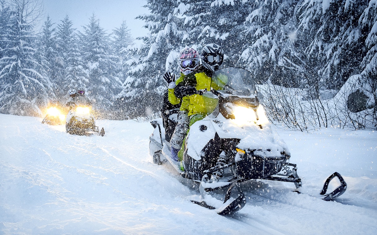 Guests riding snowmobiles through snowy forest in Zakopane.