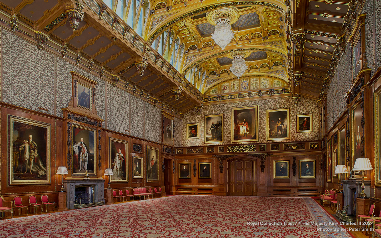 Grand hall with ornate ceiling and historic portraits at Windsor Castle, England.
