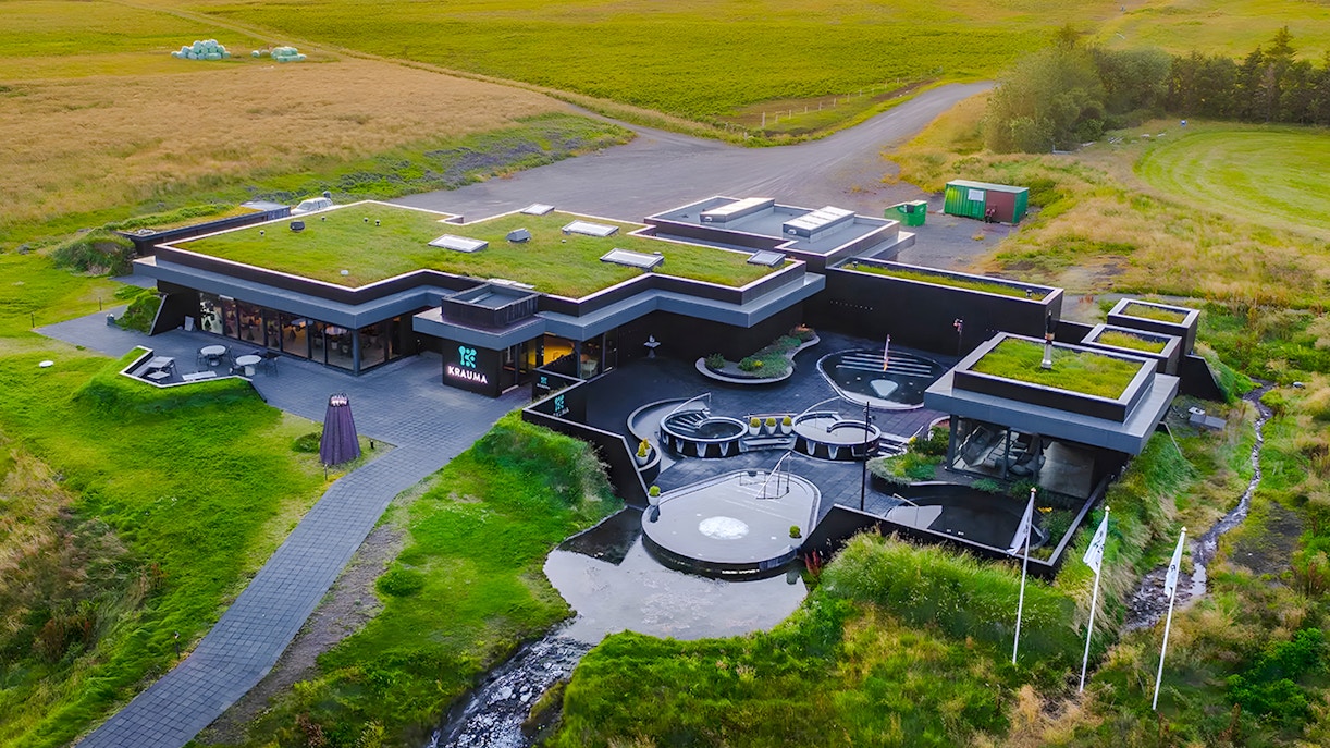 Krauma Geothermal Baths complex surrounded by green landscape in Iceland.
