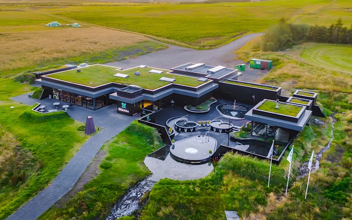 Krauma Geothermal Baths complex surrounded by green landscape in Iceland.