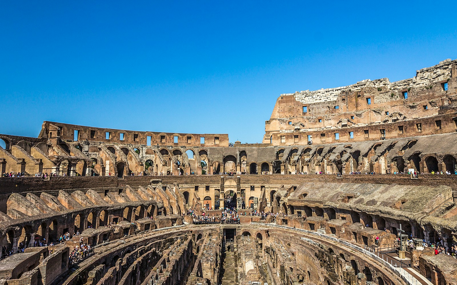 Visite du Colisée avec des visiteur·euse·s entrant par l'entrée des gladiateurs sur le sol de l'arène à Rome.