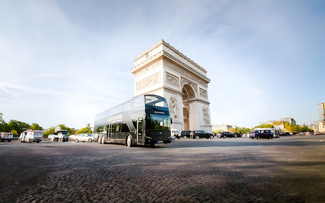 Bustronome bus driving past Arc de Triomphe in Paris.