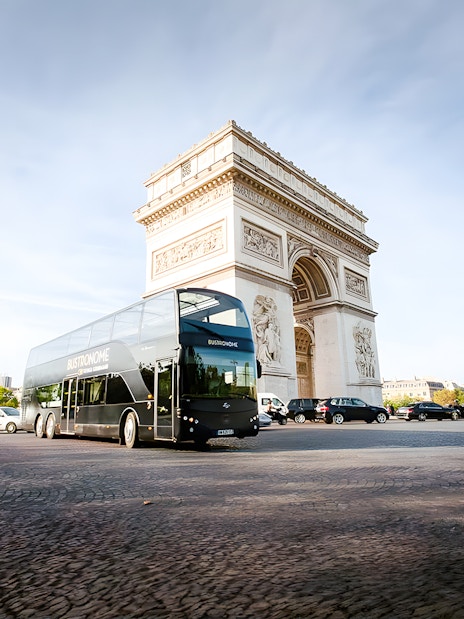 Bustronome bus driving past Arc de Triomphe in Paris.