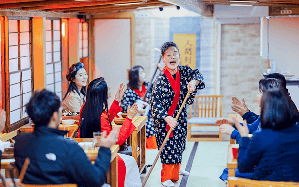Traditional Japanese dance performance on a boat with audience clapping in appreciation.