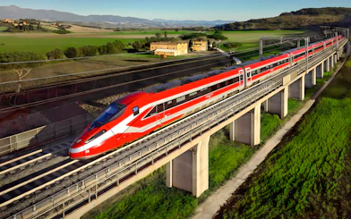 Trenitalia Frecciarossa train crossing a bridge in the Italian countryside.
