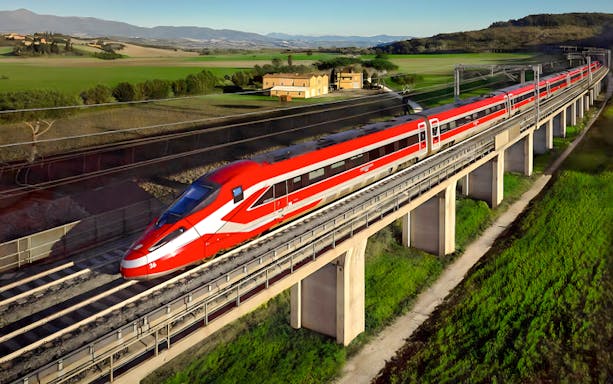 Trenitalia Frecciarossa train crossing a bridge in the Italian countryside.