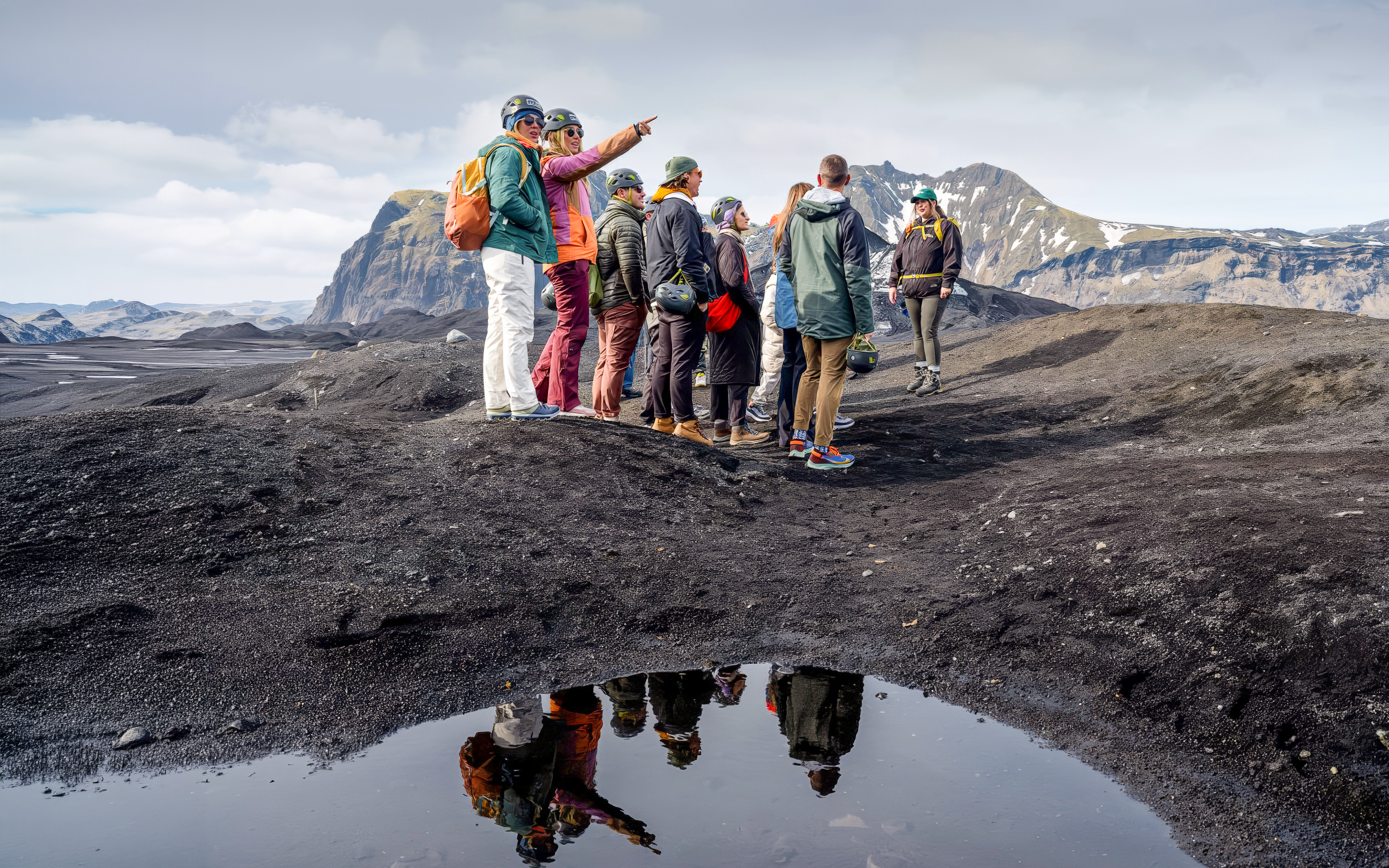 Group hiking on Sólheimajökull glacier, Iceland, with mountainous backdrop.