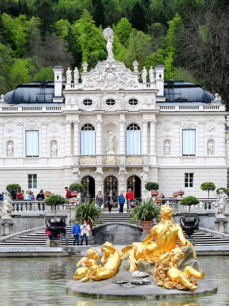 Linderhof Palace exterior with golden fountain statues in Bavaria, Germany.