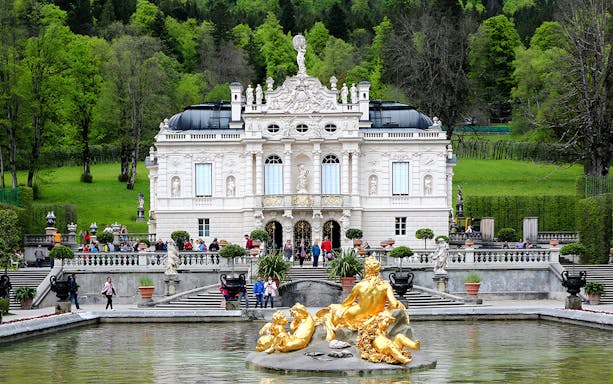 Linderhof Palace exterior with golden fountain statues in Bavaria, Germany.