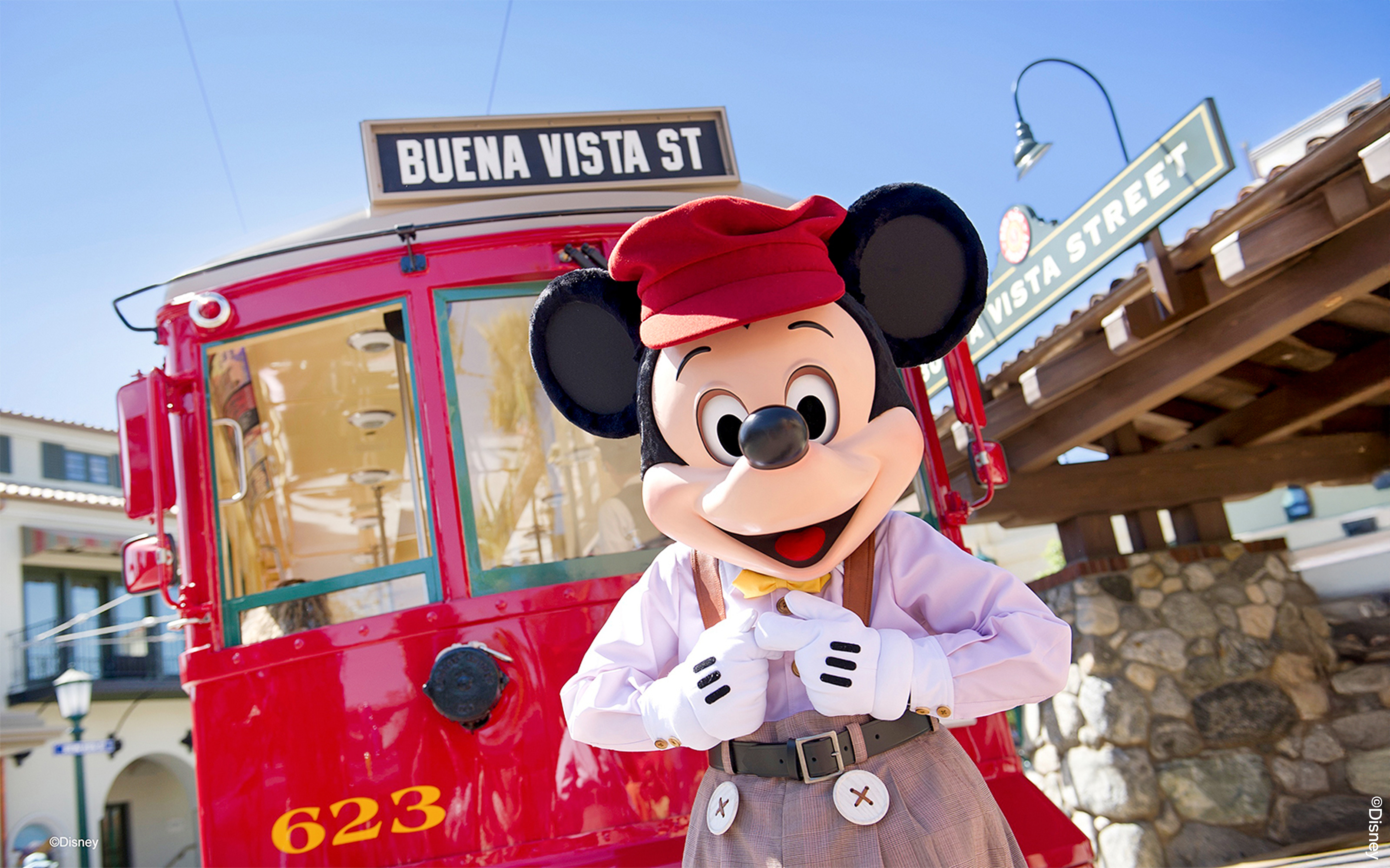Mickey Mouse in front of the Buena Vista Street train ride at Disneyland Park, California.