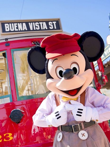 Mickey Mouse in front of the Buena Vista Street train ride at Disneyland Park, California.
