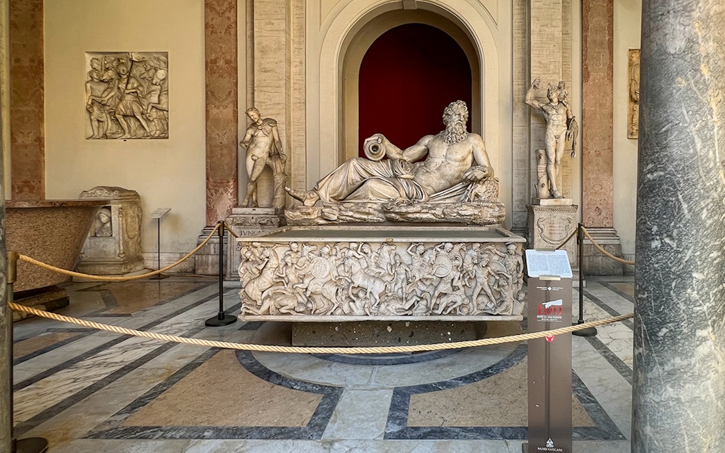 Marble statue of River God Arno at Vatican Museums, surrounded by detailed carvings.