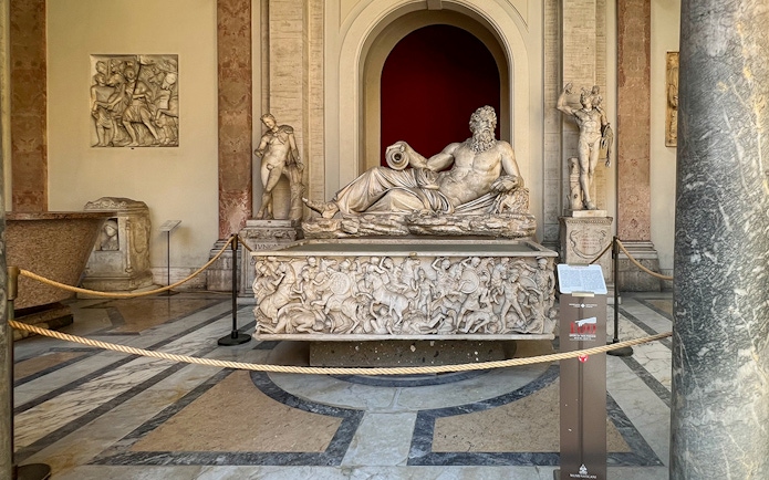 Marble statue of River God Arno at Vatican Museums, surrounded by detailed carvings.