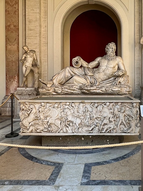 Marble statue of River God Arno at Vatican Museums, surrounded by detailed carvings.