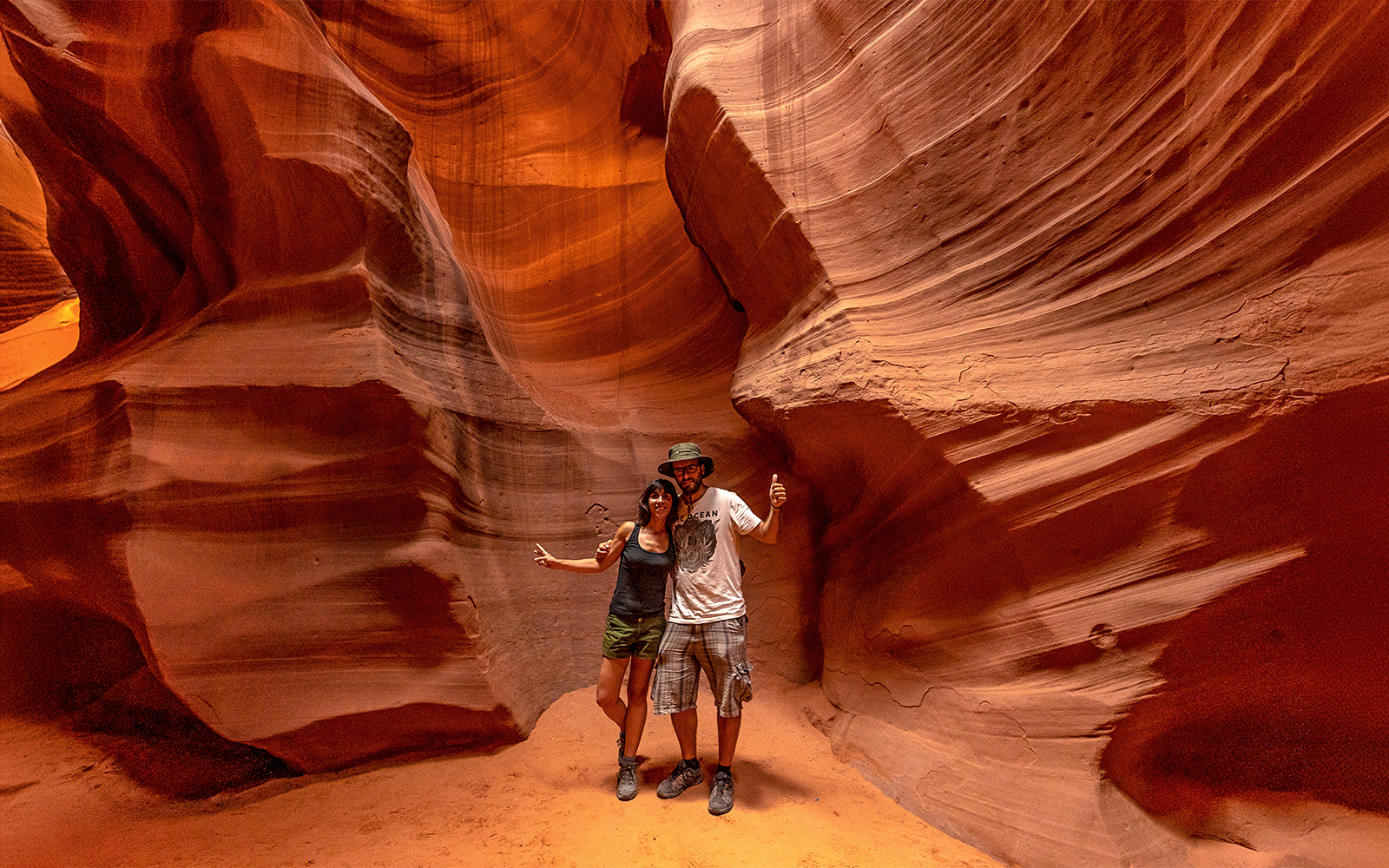 Couple exploring Upper Antelope Canyon's sandstone formations in Page, Arizona.