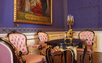 Gödöllő Royal Palace interior with ornate chairs and table.